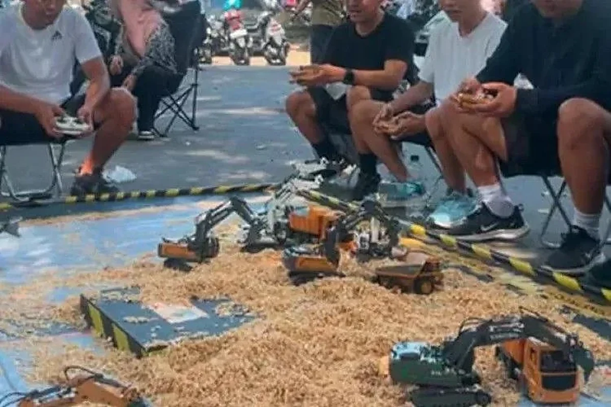 Arena demo RC excavator miniatur di atas terpal dengan pembatas kuning-hitam - pengoperasian unit dengan remote control