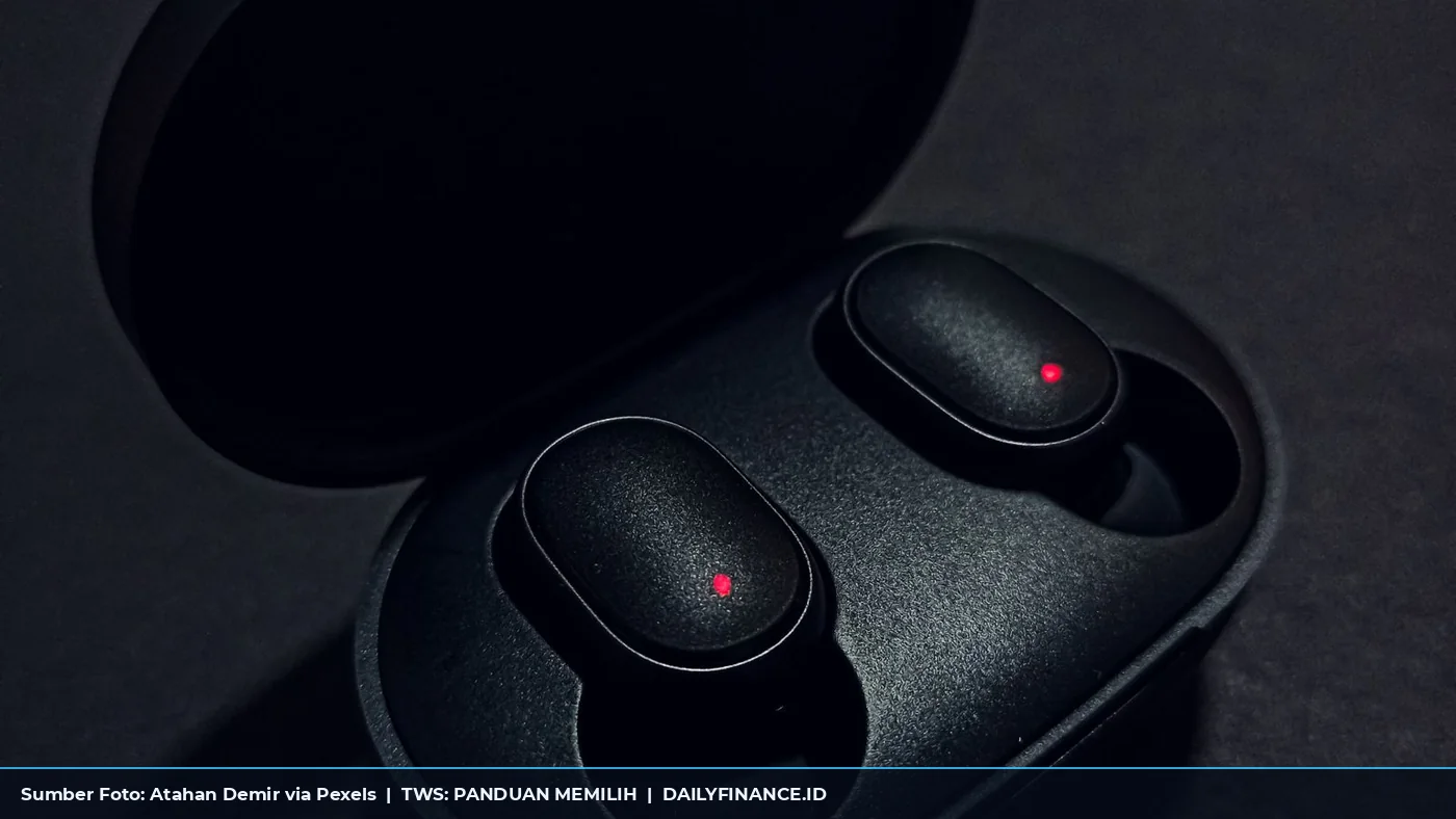 Earphone nirkabel hitam di dalam charging case terbuka di atas permukaan gelap