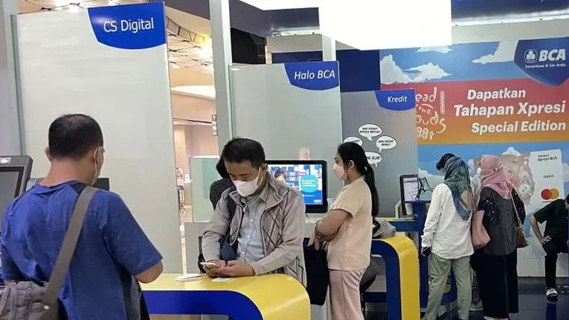 Nasabah bertransaksi di area layanan mandiri BCA dengan tanda CS Digital, Halo BCA, dan Kredit pada partisi berwarna biru dan putih