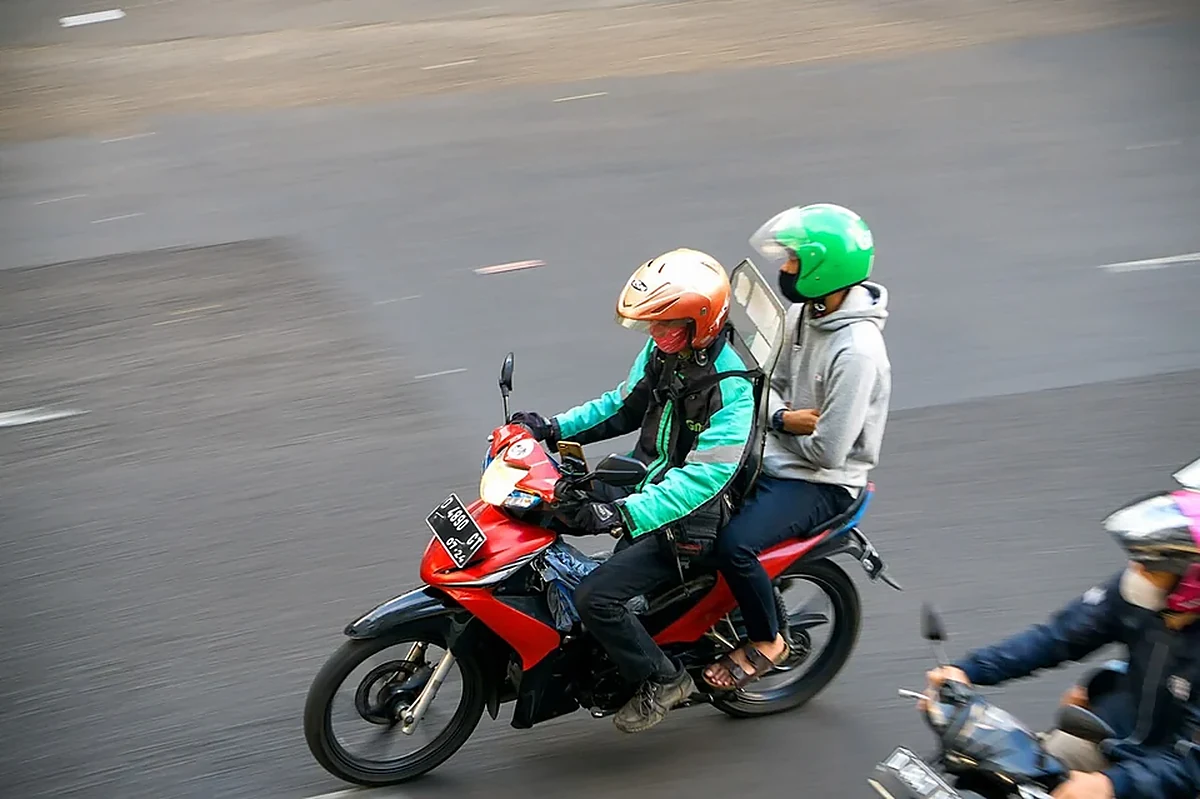 Driver ojek online melintas di jalan - side job untuk karyawan kantoran