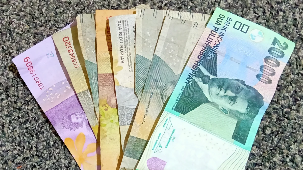 Lembar uang rupiah kertas pecahan kecil dan besar ditata berjajar di atas permukaan