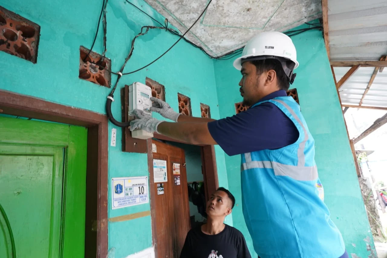 Petugas listrik memeriksa meteran prabayar di rumah warga