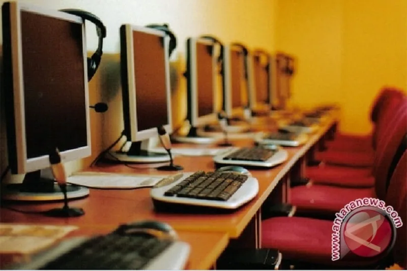 Deretan komputer warnet tradisional Indonesia dengan kursi dan headset siap dipakai pelanggan